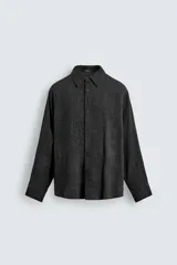 Camisa de corte relajado con diseño de cuadros en tonos negro y beige, cuello camisero, manga larga y cierre frontal de botones.