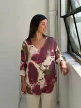 Sweater de punto con cuello en V y mangas tres cuartos con dobladillo. Presenta un estampado abstracto con manchas en tonos bordó, marrón y crema.