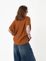 Chaleco tipo poncho de tejido de punto color tostado, con cuello polera y diseño holgado con laterales abiertos.