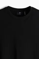 Remera de punto liviano color negro, con cuello redondo ribeteado, mangas cortas y bajo recto. Corte estándar y silueta clásica.