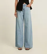 Pantalón de jean de corte wide leg, tiro alto, con bolsillos delanteros y traseros, trabillas para cinturón y cierre frontal con cremallera y botón.