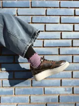 Zapatillas deportivas de cuero color peltre, con cordones negros y suela de goma blanca.