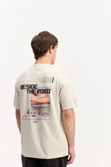 Remera de manga corta color beige, con estampa en la espalda que incluye un paisaje marino de atardecer y texto.