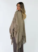Ruana gris de tejido punto con detalles en relieve y flecos en el ruedo.