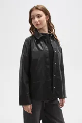 Sobrecamisa de cuero sintético en tono bordó oscuro, con cuello clásico, cierre frontal oculto y un bolsillo aplicado en el pecho. Presenta un corte holgado con mangas largas y puños rectos.