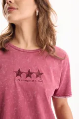 Remera de algodón color rojo con efecto acid wash, de corte cropped y manga corta. Presenta un estampado de tres estrellas en el pecho con la frase 'life is magic as a star' y detalles de costuras en contraste en las mangas y el ruedo.