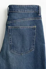 Jean wide leg de tiro alto en denim de algodón con ligero stretch, cinco bolsillos, lavado azul con efecto deslavado y terminación desmechada en el bajo.