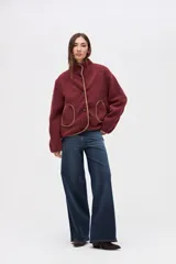 Campera de sherpa doble faz color bordó, con cierre frontal de botones, cuello alto y bolsillos laterales. Presenta detalles de vivos en nylon color tostado en los bordes y costuras.