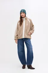 Campera de sherpa doble faz con diseño capitoneado, cuello alto y cierre frontal. Presenta detalles en nylon a contratono en la cartera central, bolsillos laterales y bandas laterales en las mangas. Cuenta con puños elásticos y calce relajado.