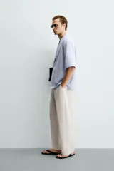 Camisa tipo kimono de corte relaxed fit, color celeste, confeccionada en tejido fluido de viscosa y lino. Presenta cuello con solapas de muesca, manga corta y cierre frontal cruzado con doble botonadura.
