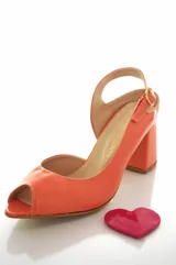 Sandalias de charol color naranja claro, con taco mediano forrado, tira ajustable al talón con hebilla dorada, puntera abierta y detalle de aplique en forma de corazón color fucsia.