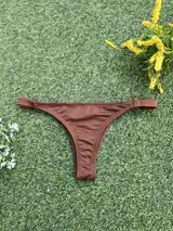 Conjunto de bikini color chocolate con textura acanalada. El corpiño es de estilo triangular con una hebilla metálica decorativa en el centro y breteles finos. La bombacha es de corte colaless con tiras laterales.