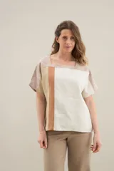 Blusa de lino de diseño contemporáneo, con escote cuadrado y mangas cortas en recortes que combinan distintas texturas. Su propuesta incorpora una franja vertical en contraste que aporta dinamismo y personalidad, mientras que el calce relajado la convierte en una prenda fresca y versátil.