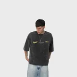 Remera de algodón con efecto acid wash gris oscuro, de corte oversize, cuello redondo, mangas cortas y estampa frontal en tono amarillo.