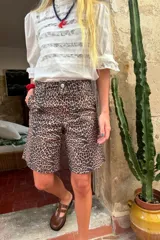 Blusa negra de manga 3/4 con cuello alto, confeccionada en algodón con paneles horizontales de encaje negro en el torso. Presenta un fajín integrado que se anuda a la cintura y puños con volado de encaje.