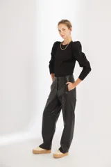 Pantalón de cuero negro de tiro medio, con fit oversized y piernas estilo slouchy, bolsillos laterales y cierre frontal.