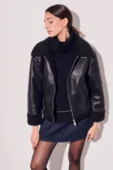 Campera negra de cuero sintético con cuello y puños de piel sintética. Corte oversize y cierre frontal con cremallera.