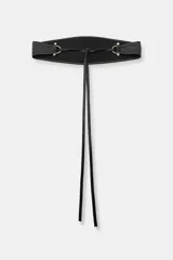 Cinturón tipo fajín ancho de piel sintética negra, con forma curva en la parte superior e inferior. Presenta detalles metálicos dorados en los laterales y se ajusta mediante lazos largos del mismo material.