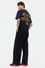 Remera boxy de algodón color negro, con cuello redondo acanalado, mangas cortas y hombros caídos. Presenta un pequeño estampado amarillo en el pecho con el texto "sports archives 08".