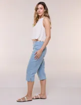 Capri de denim blanco con pretina ancha elastizada, tiro alto, bolsillos simulados al frente y bolsillos funcionales en la parte posterior, con pequeños tajos laterales en el bajo.
