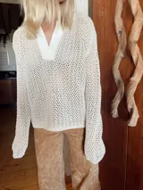 Buzo de tejido de punto calado color beige claro, con cuello tipo polo en color blanco. Manga larga.