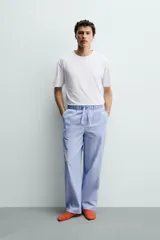 Set de pijama para hombre compuesto por una remera blanca de cuello redondo y mangas cortas, y un pantalón celeste a rayas verticales con cintura elástica y bolsillos laterales.
