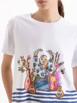 Remera de algodón pima blanco, de corte regular y escote redondo, con un diseño gráfico frontal que incluye una figura estilo Buda rodeada de flores y jarrones sobre rayas marineras.