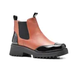 Bota corta color marrón con puntera y talón en charol negro, elástico lateral negro, suela track y tirador trasero.