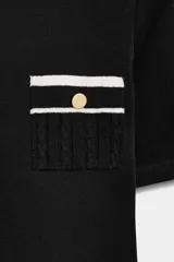 Camiseta negra de manga corta y corte slim fit, con cuello redondo ribeteado en blanco y dos bolsillos de plastrón en el pecho con un botón dorado cada uno.