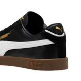 Championes Puma modelo Club Li Era, con diseño de perfil bajo en color negro, franja lateral blanca característica de la marca y suela de goma color caramelo. Presenta detalles en dorado en el logo lateral y la lengüeta.