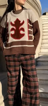 Sweater de punto con diseño color block en tonos marrón y beige, con detalle central de aplique de cuero con contorno bordado a mano.
