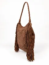 Cartera tipo hobo de cuero vacuno color tostado, con diseño amplio y flexible, decorada con un trenzado artesanal en el frente y largos flecos laterales. Cuenta con correa larga para llevar al hombro.