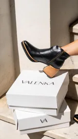 Botinetas de cuero negro con diseño combinado en textura reptil, taco cuadrado de madera y cierre lateral.