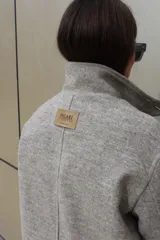 Campera de paño de lana color marrón con diseño oversize. Presenta cuello alto, cierre frontal con botones y detalles en pana azul marino en los puños y en las tapas de los bolsillos frontales.