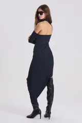 Vestido negro de silueta ajustada, largo midi, con un hombro descubierto y manga larga. Presenta drapeado en la falda y terminación irregular.