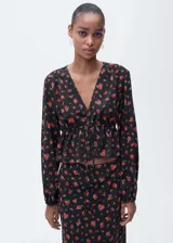 Blusa crop de viscosa con estampado floral, cuello en pico, manga larga con puños elásticos y detalle de lazo ajustable en la cintura con fruncido.