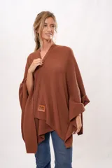 Ruana tejida de punto color marrón con etiqueta de cuero con el logo de la marca en la parte inferior.