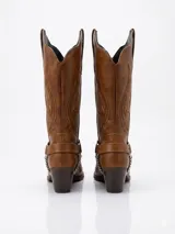 Bota estilo texana de caña alta, color marrón, con bordados decorativos en el cuerpo y una correa con argolla y cadena metálica en el tobillo. Presenta taco cuadrado y punta ligeramente afinada.