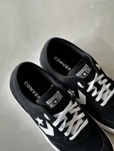 Championes urbanos Converse Net Star, de caña baja, color negro con detalles en blanco. Capellada de lona de algodón combinada con gamuza, logo Star Chevron aplicado, cordones de poliéster blancos y suela de caucho.