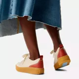 Zapatillas urbanas de cuero color crema con detalles en naranja y celeste. Suela de goma color caramelo con plataforma baja.