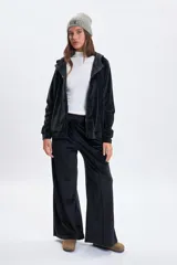 Pantalón deportivo de corte ancho confeccionado en tela plush negra, con detalle de nervio frontal y cintura elástica.