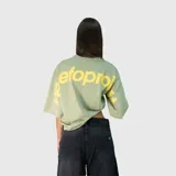 Remera de corte oversize color verde, con estampa tipográfica en color amarillo en la parte superior de la espalda.