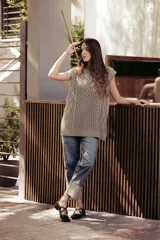 Chaleco de punto color beige, con cuello redondo, sisa amplia y corte relajado. Presenta un tejido texturizado con patrones geométricos.