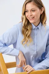 Camisa celeste rayada de corte holgado, con cuello camisero clásico y mangas largas.
