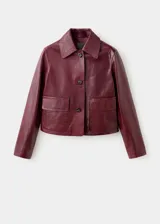 Chaqueta de cuero de corte recto con cuello camisero, cierre frontal de botones y dos bolsillos de parche con solapa en la parte delantera.