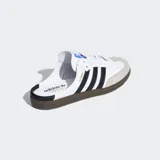 Zuecos Adidas Samba OG en color blanco con las tres tiras negras, puntera de gamuza gris y suela de goma marrón, con diseño destalonado.
