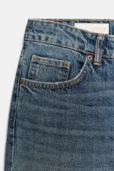 Jeans de tiro bajo con corte wide leg y largo cropped. Presenta diseño de cinco bolsillos, trabillas para cinturón y cierre frontal con cremallera y botón metálico.