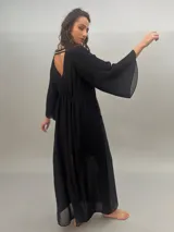 Vestido largo de gasa negra con estampado abstracto color dorado. Presenta mangas largas plisadas, escote cuadrado, tajo lateral y forro interior.