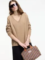 Sweater color beige de hilo con textura brillosa, escote en V y manga larga.