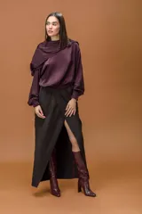 Blusa de tela satinada color violeta oscuro, con cuello drapeado amplio y mangas largas con puños elásticos.